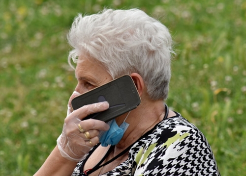 elderly woman wearing face mask on a cell phone